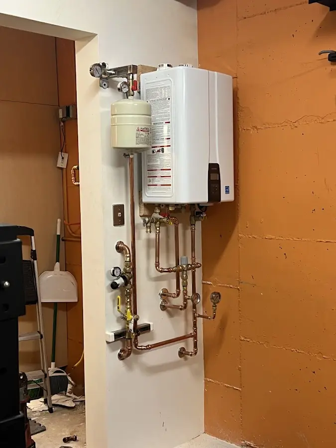 Plumbing technician inspecting water heater connections in Summit View